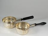 pair of silver saucepans with black handles on a white background