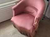 a pink chair that is sitting in front of a window