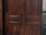 une armoire en bois à côté d'une table et d'une chaise dans une pièce
