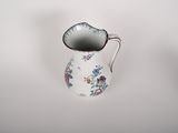 a small white pitcher with a floral design on it