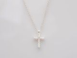 un pendentif en forme de croix avec un diamant blanc, monté sur une chaîne en argent