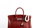 un sac à main en cuir de crocodile rouge, avec une corde blanche suspendue à la poignée