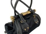 Le petit sac à main noir est muni d'une poignée dorée.