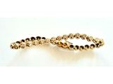 gros plan d'un bracelet en or sur une surface blanche