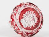a red glass vase with a white flower on it