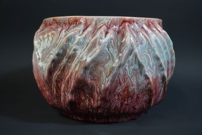 a close up of a red and white vase on a black background