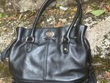 a black handbag sitting on the ground next to a stone wall