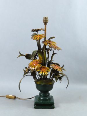 un vase contenant des fleurs, posé sur une table où se trouve une lampe