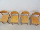 four wooden chairs are lined up against a white wall