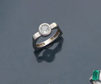 un gros plan d'une bague sertie d'un diamant et d'une émeraude sur une surface noire