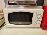 un micro-ondes blanc posé sur un plan de travail, à côté d'un four à micro-ondes rouge