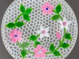 une assiette blanche décorée de fleurs roses et de feuilles vertes