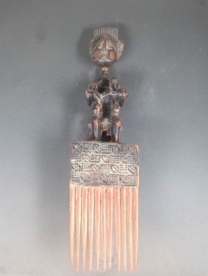 un peigne en argent surmonté d'une statuette