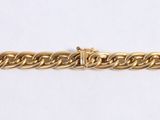 a close up of a gold chain bracelet on a white surface