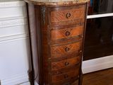 a tall wooden chest of drawers in the corner of a room
