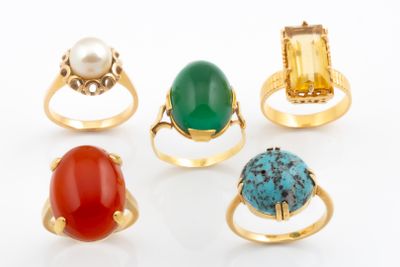 five rings with different colored stones on them on a white surface