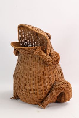 a wicker bag with a cat sitting inside of it