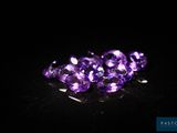 un gros plan sur un bouquet de pierres précieuses violettes posées sur une surface noire