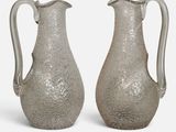une paire de vases en verre argenté posés sur une surface blanche, sur fond blanc