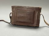 an old brown leather purse with a strap on a white surface