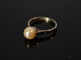 un gros plan d'une bague ornée d'une perle sur un fond noir