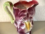 un vase violet muni d'une anse verte, posé sur une table