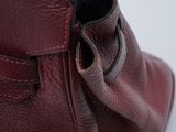 someone is holding a red purse with a black handle on a white surface