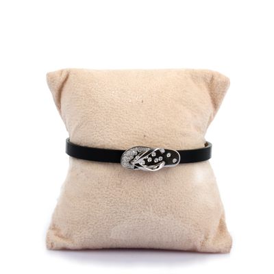 bracelet en cuir noir avec une boucle en argent posé sur un coussin blanc