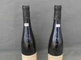 two bottles of wine sitting on top of a table next to each other