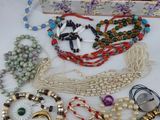 many different necklaces and bracelets laid out on a table