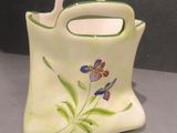 un petit vase muni d'une anse sur laquelle est peinte une fleur