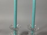 une paire de bougeoirs en verre surmontés de bougies de couleur turquoise posées l'une sur l'autre