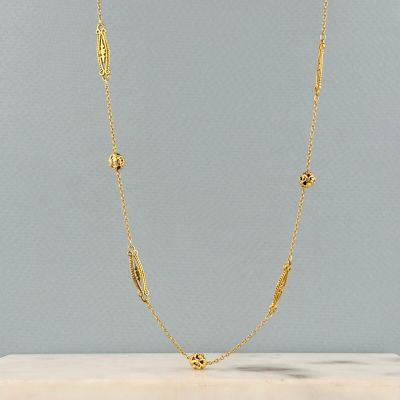 un collier plaqué or posé sur une surface en marbre
