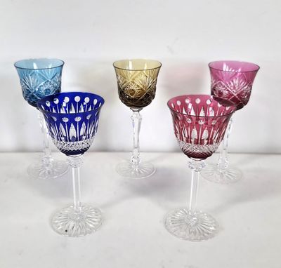 four different colored glass goblets are lined up on a white surface