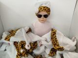 un bébé vêtu d'une serviette et portant des lunettes de soleil, assis au milieu d'un tas de peluches