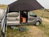 a van that is parked in the grass with a tent over it