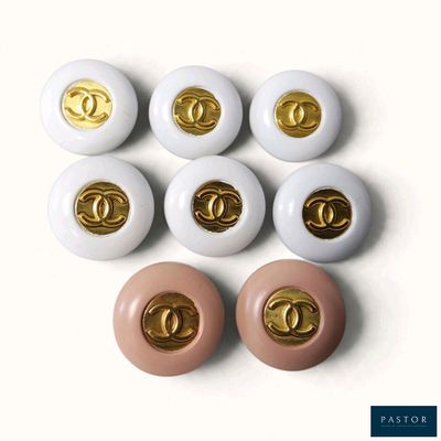 six paires de boutons blancs et dorés arborant le logo Chanel