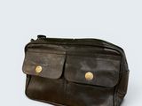 the black leather bag is sitting on a white surface