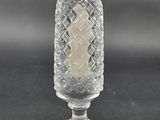 a clear glass candle holder with a cross on top