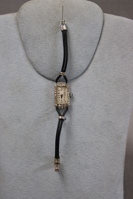 an image of a woman ' s necklace with a watch attached to it