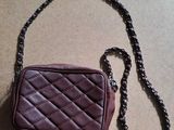 maroon leather purse with chain strap on a tan surface