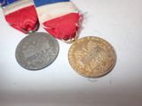 two medals on a white table with a red, white and blue ribbon