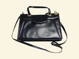 black leather handbag on a white background with a strap