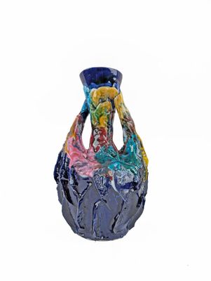 a blue vase with a multicolored design sitting on a white surface