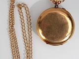 gold plated pocket watch and chain on a white surface