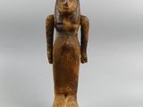 a statue of a woman in a long dress stands on a wooden base