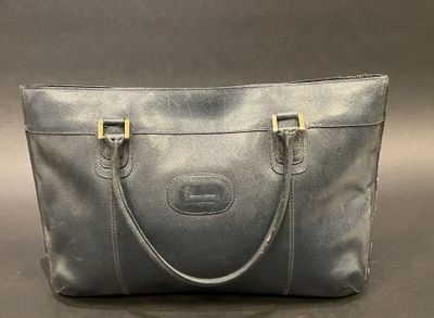 a grey leather handbag with gold handles on a gray background