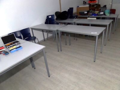 de nombreuses tables et chaises dans une pièce, avec un ordinateur portable posé sur une table