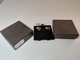 two pieces of jewelry sitting on top of a table next to a box