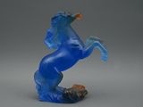 statue d'un cheval bleu posé sur un rocher, sur fond gris